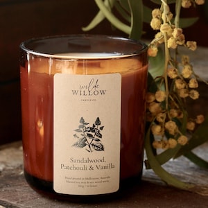 May include: A brown glass candle jar with a label that reads "wilde WILLOW CANDLE CO" and "Sandalwood, Patchouli & Vanilla". The label also states "Hand poured in Melbourne, Australia. Natural soy wax & eco wood wick. 300g / 50 hours."