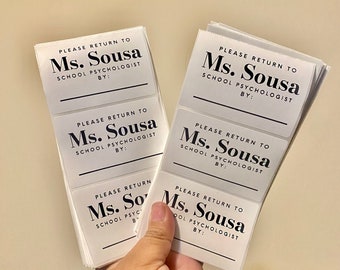 May include: A stack of white rectangular stickers with black text that reads "PLEASE RETURN TO Ms. Sousa SCHOOL PSYCHOLOGIST BY:"