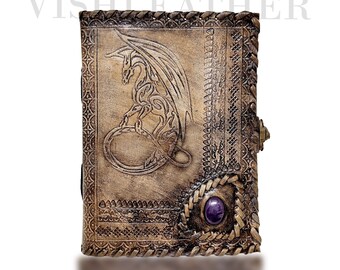 May include: A brown leather journal with a dragon design embossed on the front cover. The journal has a purple gemstone on the bottom right corner and a brass clasp on the right side.