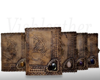 May include: Five leather-bound journals with dragon designs and gemstone accents. The journals are brown with intricate embossed details and each has a different colored gemstone on the front cover.
