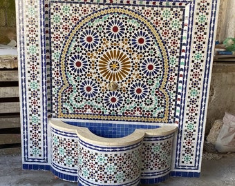 May include: A decorative wall fountain made of mosaic tiles in shades of blue, white, red, green, and yellow. The fountain features a traditional Moroccan design with intricate geometric patterns.