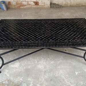 May include: Black mosaic tile top coffee table with a black metal frame. The table has a geometric pattern and a simple design.