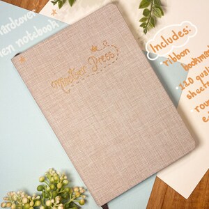 May include: A beige linen A5 hardcover notebook with gold lettering that says "master Press". The notebook includes a ribbon bookmark, 120 quality sheets, and rounded edges.