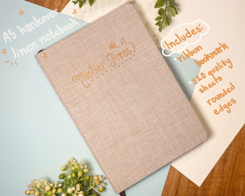 May include: A beige linen A5 hardcover notebook with gold lettering that says "master Press". The notebook includes a ribbon bookmark, 120 quality sheets, and rounded edges.