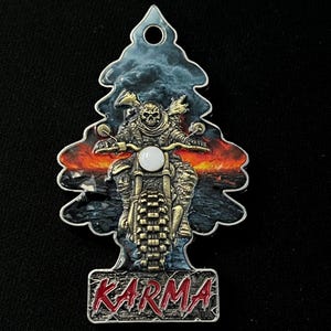 May include: Air freshener with a motorcycle theme. The design features a skeleton riding a motorcycle against a backdrop of a fiery sunset and stormy sky. The word "KARMA" is displayed in red letters at the bottom.