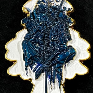 May include: A tree-shaped pendant with a gold border, white background, and a detailed blue illustration of a warrior. The word "Resurrection" is written in gold at the bottom. The pendant has a hole at the top.