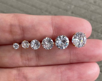 Puede incluir: Un conjunto de seis pendientes de botón de oro con piedras redondas de circonita cúbica transparentes de diferentes tamaños.