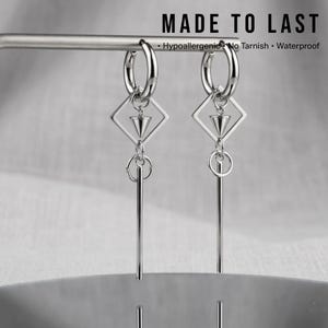 May include: Silver hoop earrings featuring geometric diamond and cone pendants, and long vertical bars. The earrings are displayed on a silver bar against a soft background. The text "MADE TO LAST" is at the top, with "Hypoallergenic No Tarnish Waterproof" below.