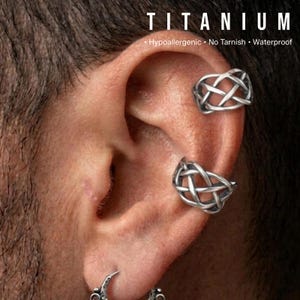 May include: Titanium ear cuffs in a Celtic knot design. The image shows two cuffs on an ear, with the word "TITANIUM" at the top, along with the words "Hypoallergenic, No Tarnish, Waterproof".