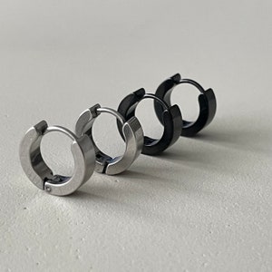 Pu&ograve; includere: Tre paia di orecchini a cerchio in fila. I primi due paia sono argentati, e il terzo paio &egrave; nero. Gli orecchini sono in metallo e hanno un design semplice e moderno. Sono mostrati su sfondo bianco.