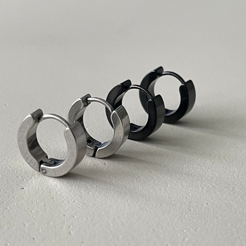Pu&ograve; includere: Tre paia di orecchini a cerchio in fila. I primi due paia sono argentati, e il terzo paio &egrave; nero. Gli orecchini sono in metallo e hanno un design semplice e moderno. Sono mostrati su sfondo bianco.
