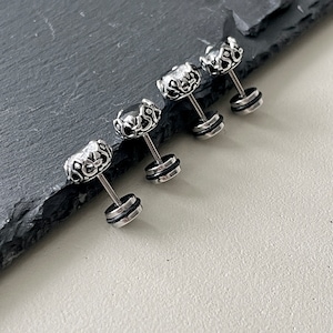 May include: Four silver and black ear studs with a crown design. The studs have a small clear stone in the center of the crown.