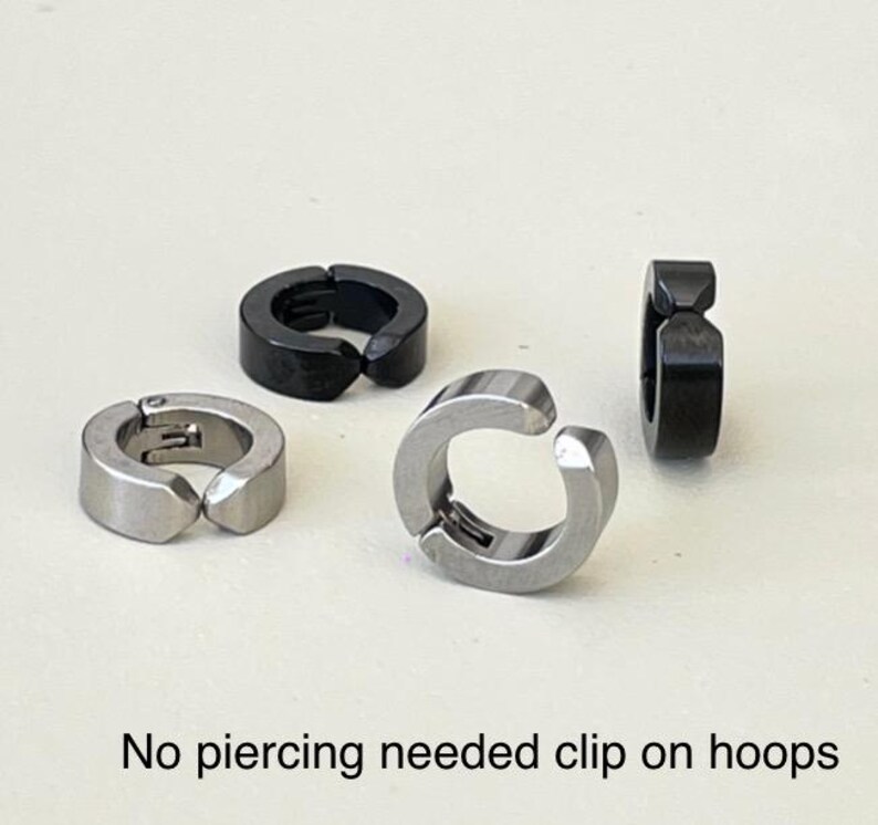 Pu&ograve; includere: Sono mostrati quattro orecchini a cerchio a clip. Due sono color argento e due sono neri. Il testo in basso nell'immagine recita "No piercing needed clip on hoops."