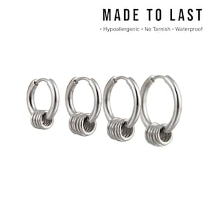 以下が含まれることがあります： 3つの小さなリングが付いた、4つのシルバーフープピアス。上部には「MADE TO LAST」の文字、下部には「低アレルギー性、変色なし、防水」の文字。白い背景に表示されています。