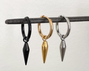 May include: Three hoop earrings with dangling spike charms, arranged in a row. The set includes one black earring, one gold-tone earring, and one silver-tone earring. Each earring features a circular hoop and a pointed, cone-shaped pendant.