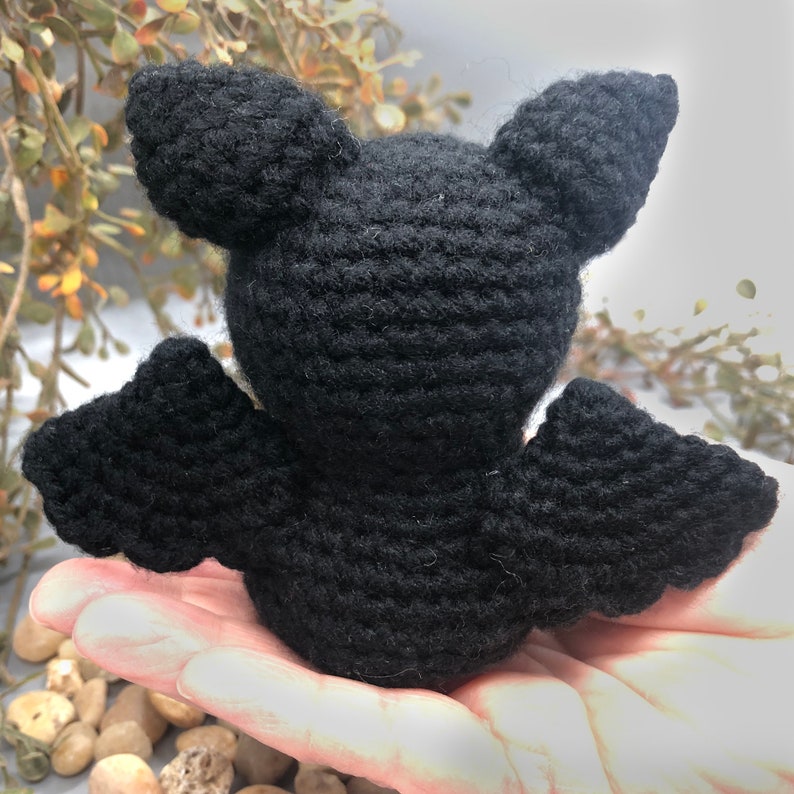 Puede incluir: Un murci&eacute;lago de crochet negro con orejas y alas grandes. El murci&eacute;lago est&aacute; sentado en una mano.