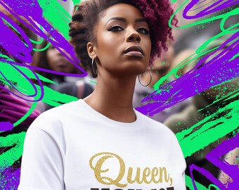 May include: A white t-shirt with the text "Queen, YOU GOT THIS" in gold glitter and dark brown lettering. The image features a woman with purple-red hair and a colorful green and purple background.