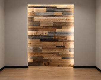 May include: A rectangular wall section covered in horizontal wooden planks of varying shades, including light tan, medium brown, and weathered gray. The wood paneling is illuminated by integrated lighting along the top and side edges of the wall.