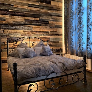 Könnte beinhalten: Ein Metallbettgestell mit einem verzierten Design, mit einem grauen gemusterten Bettbezug und weißen Kissen. Das Bett steht in einem Zimmer mit einer Holzvertäfelung und blauen Vorhängen.