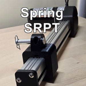 May include: A mechanical device with the text "Spring SRPT" in white. The device features a silver metal rail, black brackets, and a cylindrical motor. A pin secures a connecting piece.