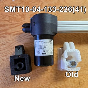 May include: A close-up of a linear actuator with a black motor and a silver rod. The actuator is labelled "SMT10-04-133-226(41)" and has a label with specifications. The image shows the new and old versions of the actuator.