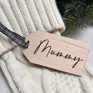 May include: A white knitted stocking with a wooden gift tag that says "Mummy" in cursive.