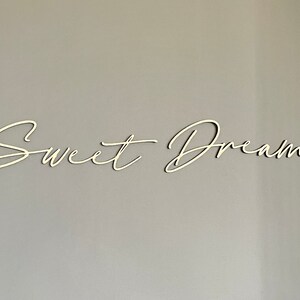 May include: White wooden sign with the words "Sweet Dreams" written in a cursive script.