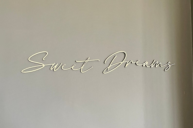 May include: White wooden sign with the words "Sweet Dreams" written in a cursive script.