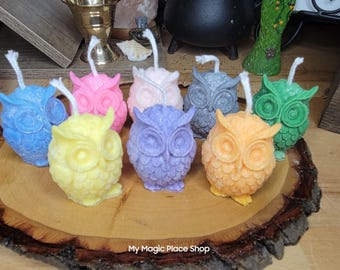 May include: Assortment of colorful owl-shaped candles, each with a different color and design. The candles are arranged on a wooden slice with the text "My Magic Place Shop".