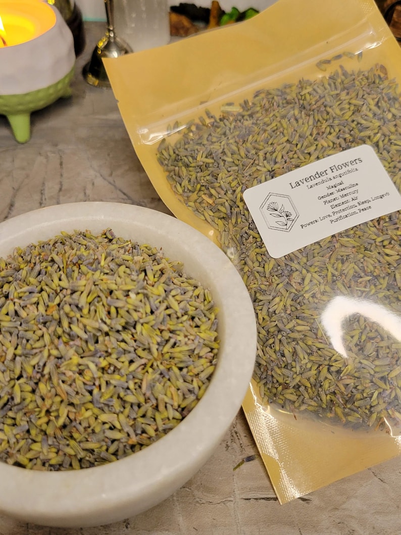 May include: A close-up of a bag of dried lavender flowers. The bag is labelled "Lavender Flowers" and lists the plant's magical properties, including its gender, planet, element, and powers. The flowers are a light purple colour and have a delicate, fragrant aroma.