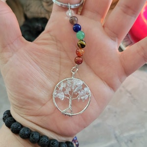 May include: A silver key chain with a clear crystal tree of life charm and a rainbow of chakra beads. The beads are clear, brown, blue, green, yellow, orange, and red.