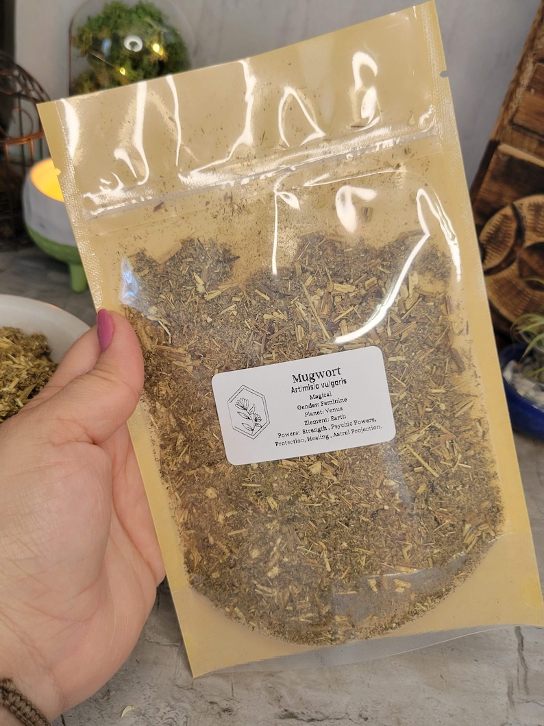 May include: A clear plastic bag filled with dried mugwort, a type of herb used in herbalism and magic. The bag has a label that reads "Mugwort, Artimisia vulgaris, Magical, Gender: Feminine, Planet: Venus, Element: Earth, Powers: Strength, Psychic Powers, Protection, Healing, Astral Projection."