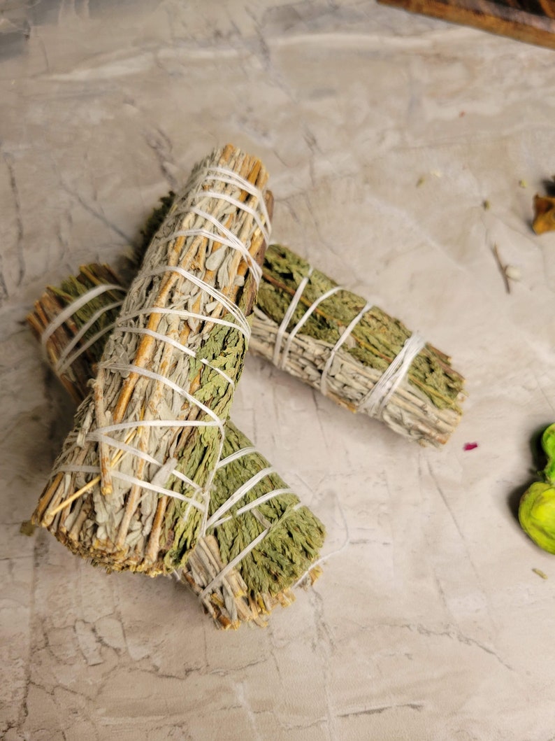 Pu&ograve; includere: Due mazzi di salvia e cedro legati insieme con uno spago. I bastoncini sono di colore marrone chiaro con foglie verdi.