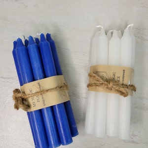 May include: Two bundles of taper candles, one blue and one white, each wrapped in a tan paper band with the text MY MAGIC PLACE UNIQUELY HANDMADE and tied with a natural jute twine bow. Each bundle contains several smooth, solid-colored wax candles.