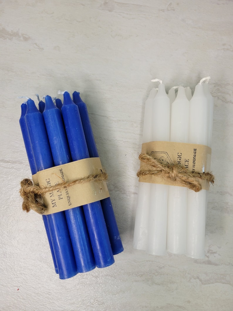May include: Two bundles of taper candles, one blue and one white, each wrapped in a tan paper band with the text MY MAGIC PLACE UNIQUELY HANDMADE and tied with a natural jute twine bow. Each bundle contains several smooth, solid-colored wax candles.