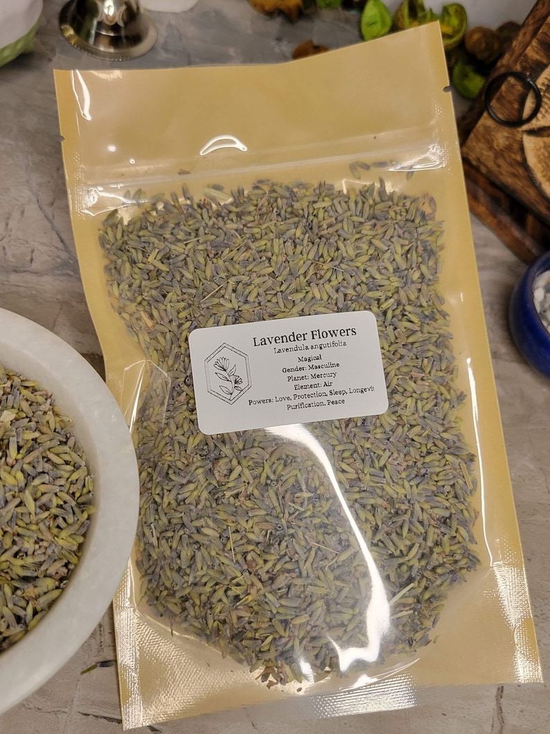 May include: A clear plastic bag filled with dried lavender flowers. The bag has a label that reads "Lavender Flowers" and includes information about the plant's magical properties, including its gender, planet, element, and powers.