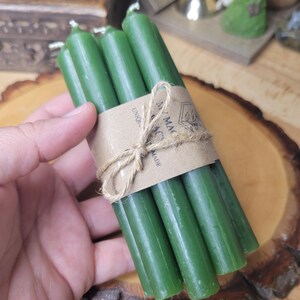 May include: A bundle of five slender, dark green taper candles held together by a brown paper band tied with a piece of natural jute twine. The paper band features the printed text My Magic Place Shop and a small graphic illustration.