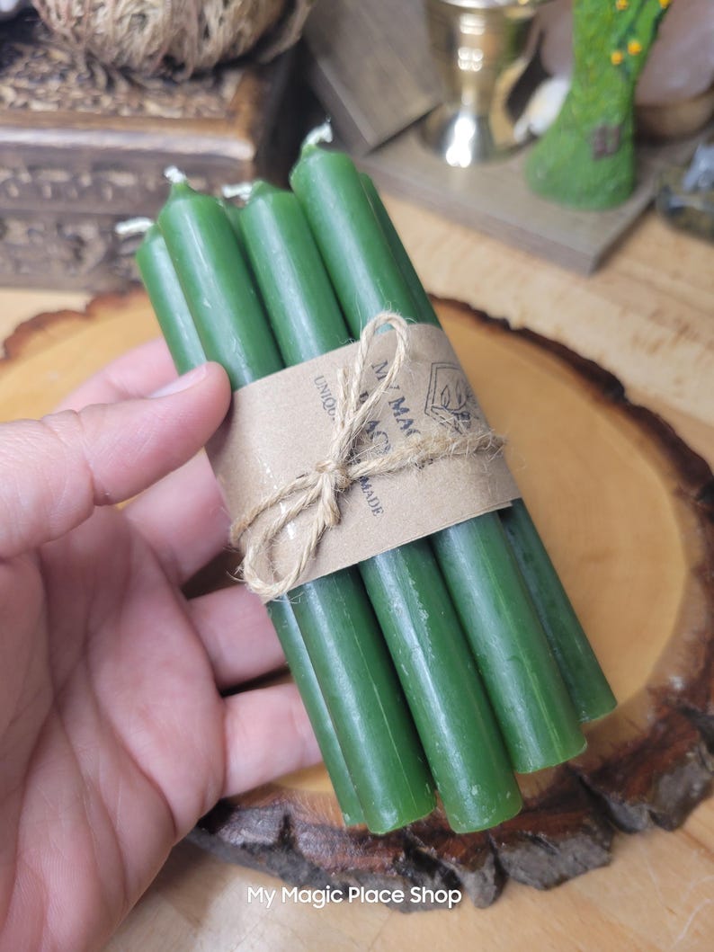 May include: A bundle of five slender, dark green taper candles held together by a brown paper band tied with a piece of natural jute twine. The paper band features the printed text My Magic Place Shop and a small graphic illustration.
