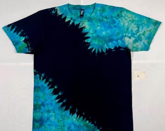 Puede incluir: Una camiseta negra tie-dye con un diseño azul y verde. El diseño está en el lado derecho de la camiseta y tiene la forma de una estrella. La camiseta es talla L.