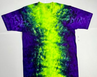 Puede incluir: Una camiseta tie-dye con una franja vertical de color amarillo y verde brillante en el centro, rodeada de un patrón tie-dye de color morado oscuro y negro.