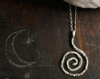 Può includere: Collana d'argento con un ciondolo a spirale. Il ciondolo è realizzato in filo ritorto e ha una superficie testurizzata.