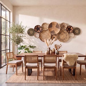 May include: A dining room set featuring a long wooden table with six chairs with cane backrests and light-coloured cushions. A collection of round woven wall baskets in various sizes and natural tones is displayed on the wall above the table.