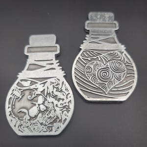 May include: Two silver metal bottle charms, one with a skull and crossbones design and the other with a swirling heart design.
