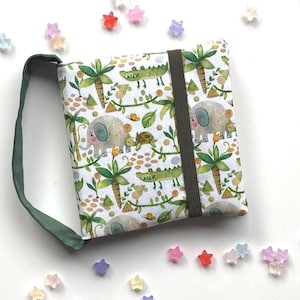 Könnte beinhalten: Eine weiße Stofftasche mit einem grünen Riemen. Die Tasche hat einen Dschungeltierdruck mit Elefanten, Krokodilen und Palmen.