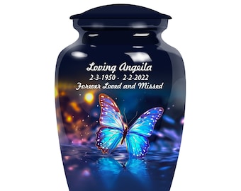Puede incluir: Una urna de cerámica azul oscuro con un diseño de mariposa. La urna tiene una inscripción blanca que dice "Loving Angeila 2-3-1950 - 2-2-2022 Forever Loved and Missed".