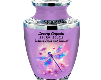 May include: Purple cremation urn with a silver lid and trim. The urn features a dragonfly with iridescent wings and pink flowers. The urn is inscribed with the text "Loving Angeleia 2-3-1950 - 2-2-2022 Forever Loved and Missed".