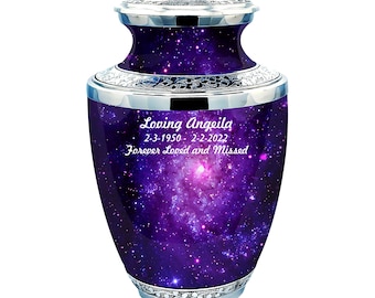 May include: Purple cremation urn with a galaxy design and silver trim. The urn is engraved with the text "Loving Angeila 2-3-1950 - 2-2-2022 Forever Loved and Missed".