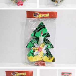 May include: Christmas decorations in clear plastic packaging. The image shows heart-shaped wreaths with ornaments, a green Christmas tree decoration with a candle, and small wreaths. The packaging has the word "Noël" on it.