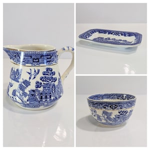 May include: A collection of blue and white ceramic tableware featuring a classic Willow pattern. The set includes a pitcher, a rectangular dish, and a small bowl. The designs depict landscapes and architectural elements.