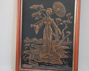May include: A framed copper relief sculpture depicting a woman in traditional Asian clothing holding an umbrella, standing in a landscape with trees and a pagoda. The sculpture is set against a black background and framed in a dark wood frame.